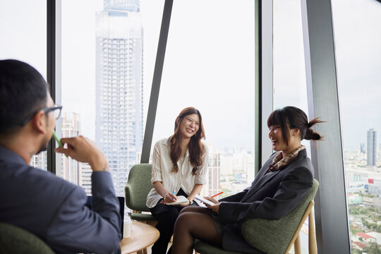 Happy businesswomen discussing strategies with manager while sitting at office