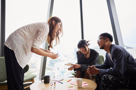 Side view of smiling businesswoman discussing strategies with team
