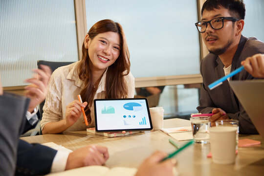 Portrait of smiling businesswoman showing digital tablet with diagrams and graphs