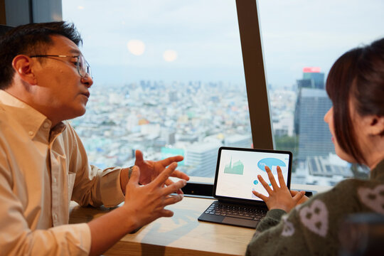 Male and female entrepreneurs discussing over pie chart diagrams on digital tablet at office