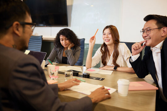 Happy entrepreneurs sitting around table in meeting room at office