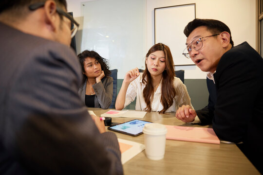 Manager explaining infographics to coworkers on digital tablet at office