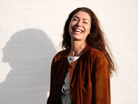 Portrait of cheerful woman against wall
