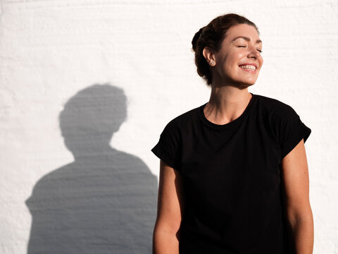 Smiling woman with eyes closed against wall
