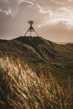 Distant view of observation post on grassy hill against cloudy sky