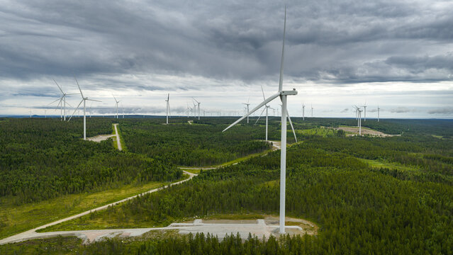 High angle view of wind turbines amidst trees under cloudy sky