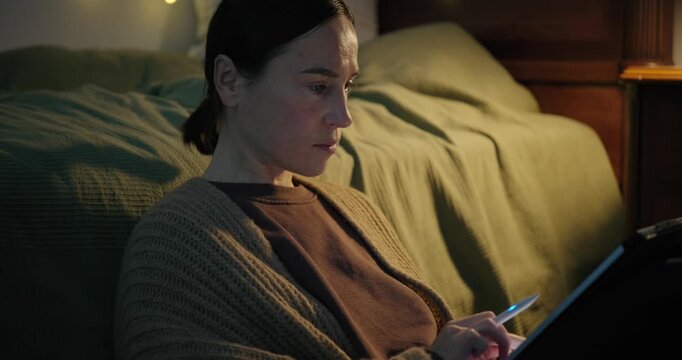 Creative Woman Working on a Digital Tablet in a Cozy Bedroom at Night