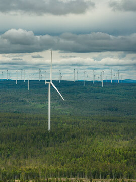 High angle view of wind turbines in row amidst trees under cloudy sky