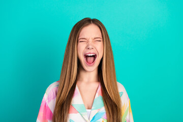 Joyful young woman with long hair expressing excitement against a vibrant teal background in a...