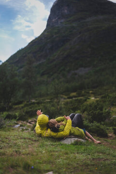 Mother and daughter lying down on grass while looking at mountain