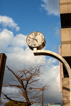 Low angle view of clock mounted on pole against sky