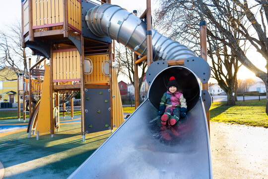 Portrait of smiling girl sliding on slide in playground