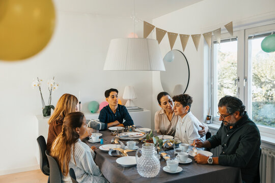 Happy family eating lunch while sitting around dining table