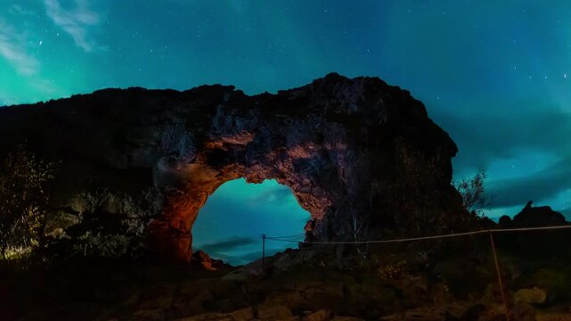 Northern lights at Hallerflot Lava field, Myvatn lake, Iceland. Dramatic glowing green sky with iconic laver hole rock formation in foreground. Time lapse dynamic motion control.
