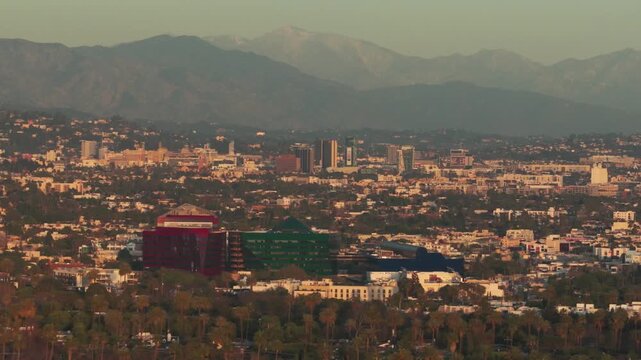 Aerial telephoto dolly shot of the Pacific Design Center in Hollywood as seen from Beverly Hills at sunset in Los Angeles, California. 4K