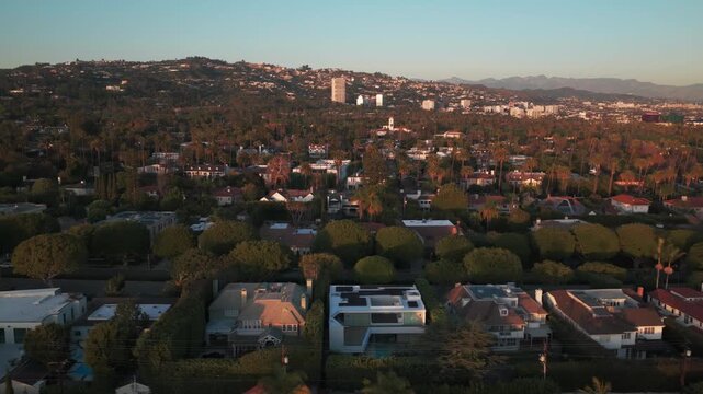 Aerial low dolly shot of mansions and estates in Beverly Hills, California at golden hour. 4K
