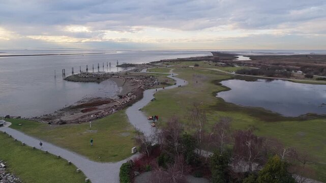 Drone flys over park on cloudy day water pond on the right anf trees below