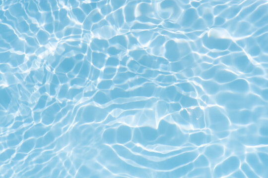 Blue water with ripples on the surface. Defocus blurred transparent blue colored clear calm water surface texture with splashes and bubbles. Water waves with shining pattern texture background.