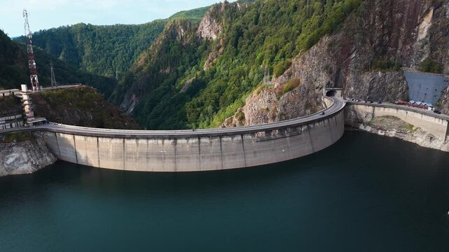 Aerial approach over Lake Vidraru toward the dam with mountains in the background.