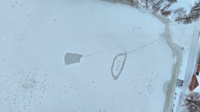 snowy frozen lake with Kate written on ice and winding shoreline in Poland Aerial view