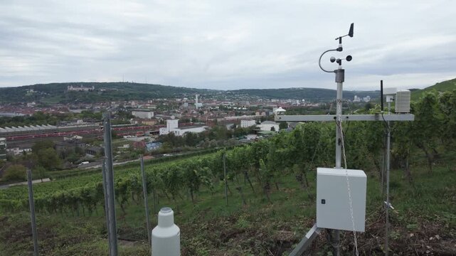 Weather station on a vineyard powered by a small solar panel. Measuring meteorological conditions such as moisture and wind. Concept of smart farming technology. Air quality and climate monitoring.