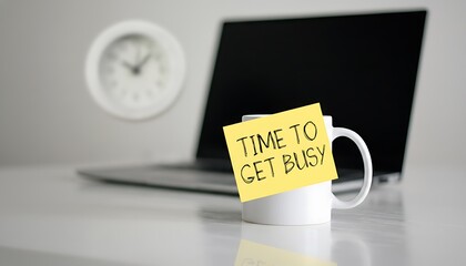 Mug with yellow sticky note saying time to get busy on office desk, laptop blurred in background and wall clock, productivity motivation concept for work and study