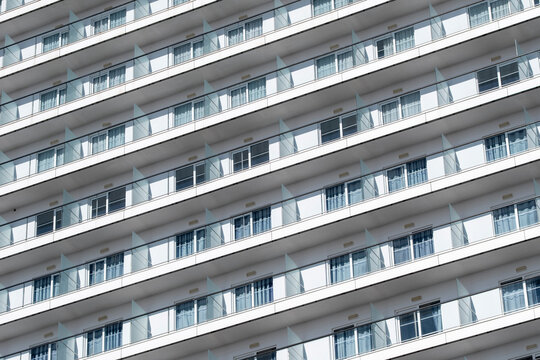 Contemporary apartment facade in Spain with long stacked balconies and glass railings creating clean horizontal rhythm and abstract pattern texture