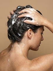 Fototapeta premium Woman applying shampoo to her hair in a bathroom setting