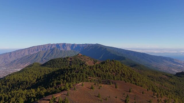 Aerial drone footage revealing volcanic landscape and distant caldera ridge in La Palma