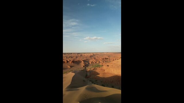 Vertical aerial orbit of Mongolian Sphinx rock in red canyon, drone shot of ancient dinosaur bones excavation site, archaeological landmark under blue sky, 4k raw unedited footage
