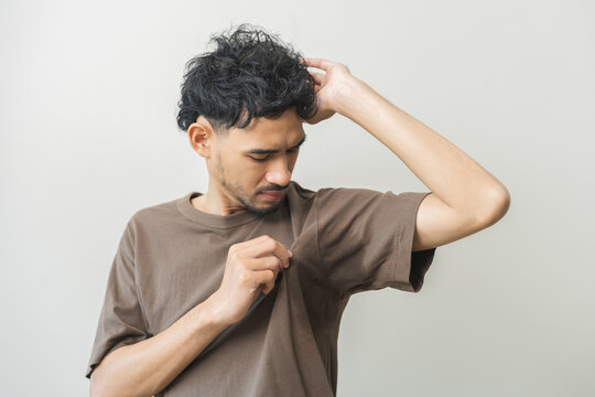 Bad smelling, deodorant asian young man smell stink, breathing nose smelly on shirt dirty stinky laundry, disgusting from clothes after washed, smelly armpit underarm Medical health, skin body care.