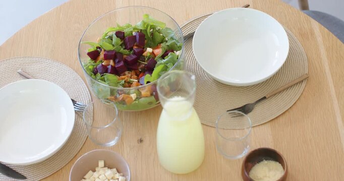 Camera is pulling back, revealing salad bowl and carafe staying centered on table, showing edge