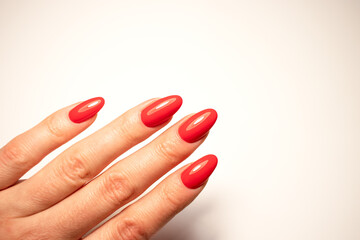 Red manicure nails on light background female hand beauty fashion style glossy polish elegant fingers salon cosmetic close up copy space