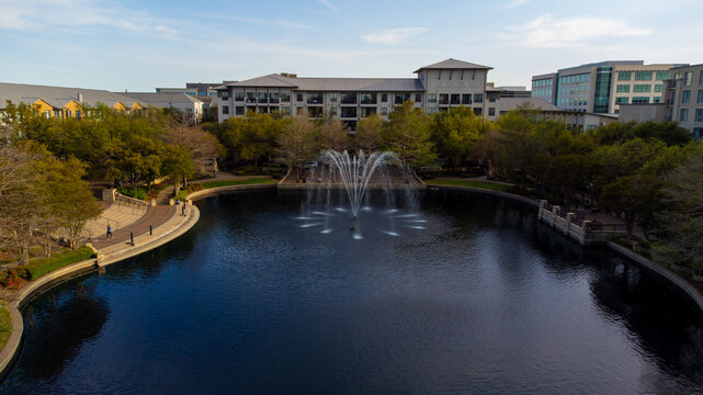 Aerial view of a fountain's shimmering spray dances on the inky water, framed by the architecture and greens of the city, Plano, Texas, United States.