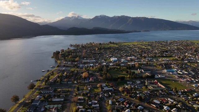 Stunning 4K 60fps drone shot of Te Anau town at golden hour, showing the gateway to Fiordland National Park bathed in sunset light with the lake and mountains