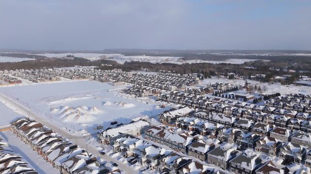 Winter aerial footage of a planned residential neighborhood in Erin, Ontario. Snow covered streets and uniform housing blocks show suburban layout, road planning, and modern residential design.