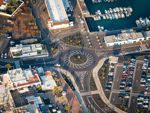 Aerial view of a vibrant roundabout, where cars navigate around a central garden near the marina, Playa Blanca, Lanzarote, Canary Islands.
