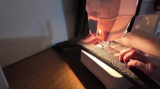 Slow motion close-up sewing machine stitching textured trim onto a handmade coat accessory