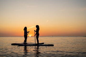 Couple of tourists young man and woman having fun paddle boarding at sea