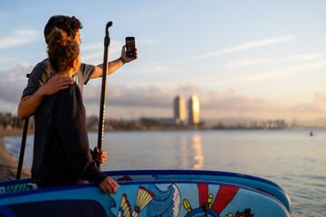 Two friends capture a social media style travel moment by taking a sunset selfie on the beach