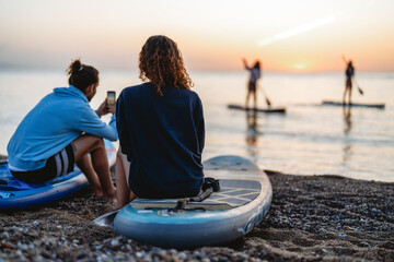Paddle boarders moving calmly across the water at sunset, mindful outdoor moment with relaxation