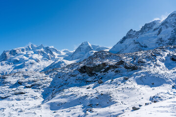 Obraz premium Switzerland winter alpine panorama of snow covered peaks and glaciers above clouds. Zermatt, Canton of Valais, Switzerland. 
