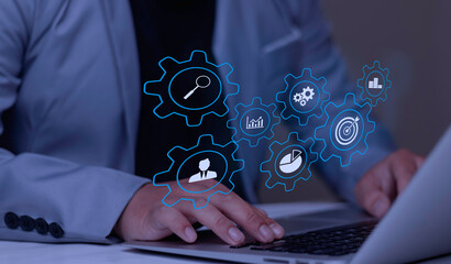 Businessman typing on laptop with virtual gears mechanism containing target, analysis, and user icons. Concept of business process automation, workflow strategy, and operational efficiency.