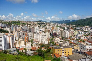 Fototapeta premium Skyscrapers and buildings in city nestled among green mountains. Pocos de Caldas, Minas Gerais, Brazil. Panoramic aerial view