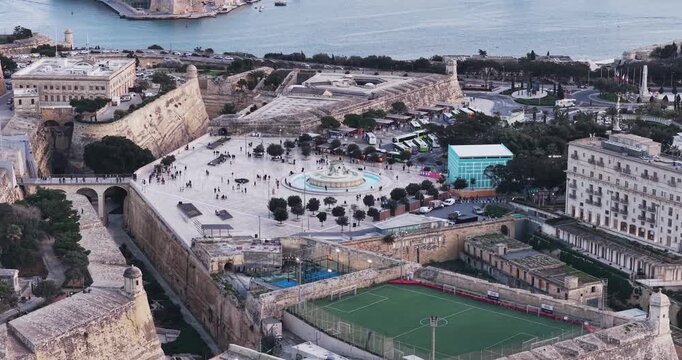 Aerial view of the majestic Valletta City Gate, with its historic stone architecture, and the iconic Triton Fountain, a bustling hub of activity, Valletta, Malta.