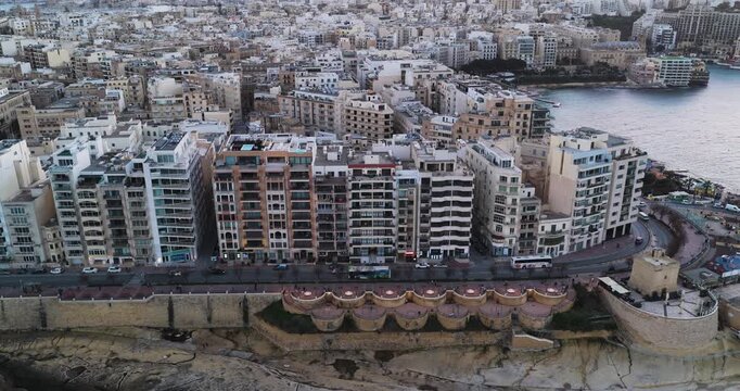 Aerial view of the coastal buildings and the medieval watchtower of St Julian's Bay, with the city stretching into the distance, St Julian's Bay, Sliema, Malta.