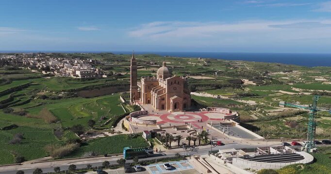 Aerial view of the Ta' Pinu Cathedral, a majestic monument rising from the green landscape with the blue sea in the backdrop, Gharb, Ta' Pinu Cathedral, Malta.