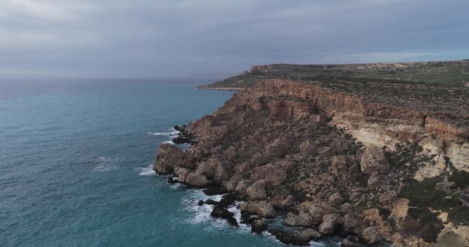 Aerial view of rugged Ras in-Niexfa cliffs meeting the turquoise sea, where the island's geology contrasts with the ocean's hues, Ras in-Niexfa, Mellieha, Malta.