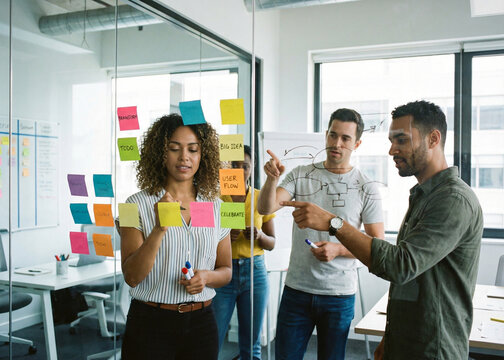Creative Business Team Brainstorming with Sticky Notes on Glass Board