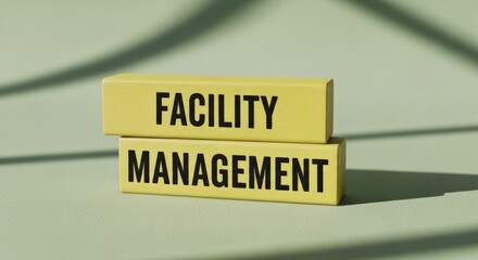 Vibrant yellow wooden blocks spelling out "FACILITY MANAGEMENT" create a contemporary, informative display on a sage green surface